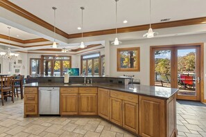 A spacious kitchen with a large island, wooden cabinets, and pendant lighting. - Hook Lane - Seven Bedroom House, Sleeps 18 (Camdenton)