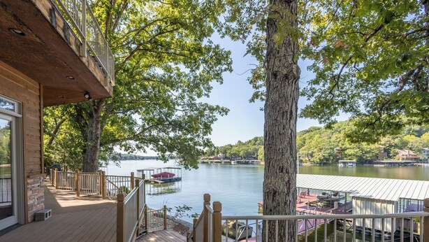 A wooden deck with a railing, overlooking a lake with boats and docked boats. - Hook Lane - Seven Bedroom House, Sleeps 18 (Camdenton)