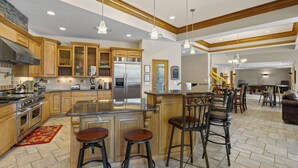 A spacious kitchen with wooden cabinets, a stainless steel refrigerator, and a central island with stools. - Hook Lane - Seven Bedroom House, Sleeps 18 (Camdenton)