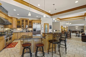 A spacious kitchen with wooden cabinets, a stainless steel refrigerator, and a central island with stools. - Hook Lane - Seven Bedroom House, Sleeps 18 (Camdenton)
