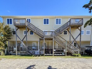 A two-story building with a central staircase, multiple windows, and a covered outdoor area.