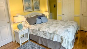 Une chambre à coucher avec un lit, une table de chevet, une lampe et deux tableaux encadrés accrochés au mur.