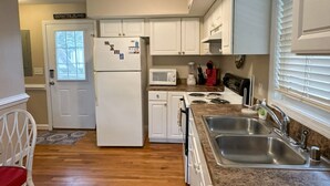 Une cuisine avec des armoires blanches, un réfrigérateur, un four à micro-ondes, une cuisinière et un évier.