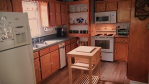 A kitchen with wooden cabinets, a refrigerator, a microwave, a stove, and a sink.