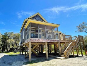 A wooden structure with a balcony and a covered area, supported by wooden stilts. - Tom Frank Gaskins: Dog friendly historic home located near the harbor. (Ocracoke)