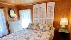 A cozy bedroom with a bed, a dresser, a mirror, and a lamp.