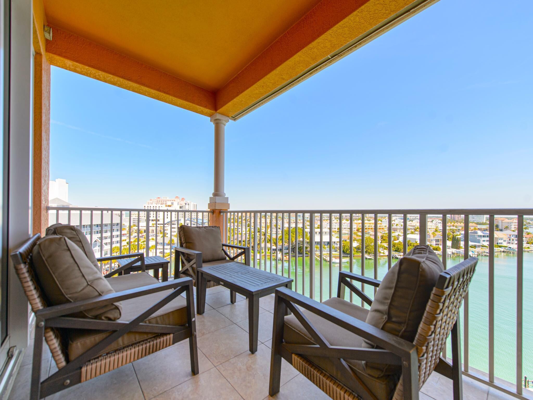 Ein Balkon mit Korbmöbeln, einem Tisch und Blick auf Stadt und Wasser.