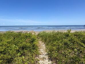 A beach path leading to the ocean with a clear sky.