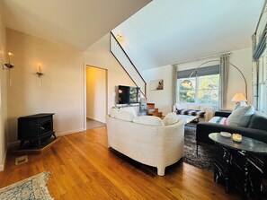 A living room with a sofa, a coffee table, a TV, a fireplace, and a staircase.