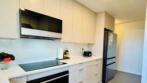 Eine moderne Küche mit weißen Schränken, einem Backofen, einer Mikrowelle und einem Kühlschrank.