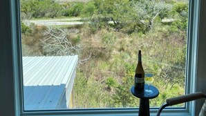 Ein Zimmer mit großem Fenster und Blick auf eine Landschaft mit einem Gebäude und Bäumen.