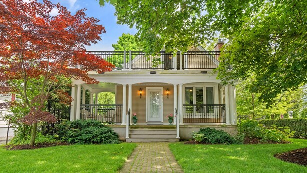 A two-story house with a covered porch, a brick pathway leading to the entrance, and a well-maintained garden.