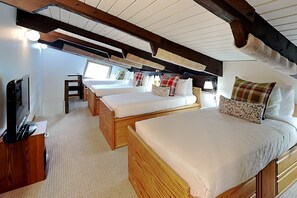 A cabin interior with three wooden beds, a television, and a window.