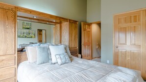 A bedroom with a large bed, wooden wardrobe, and a mirror. - Alpine Villa Condo 24 - Snug as a Bug in this Homey Remodeled Pad (Ketchum)