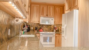 A kitchen with wooden cabinets, a stainless steel sink, a microwave, a stove, and a refrigerator. - Alpine Villa Condo 24 - Snug as a Bug in this Homey Remodeled Pad (Ketchum)