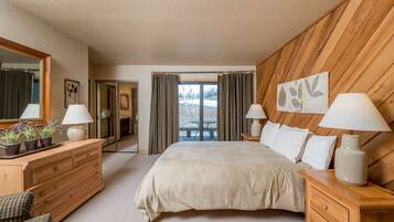 A bedroom with a large bed, wooden headboard, two bedside tables with lamps, a dresser, and a mirror.