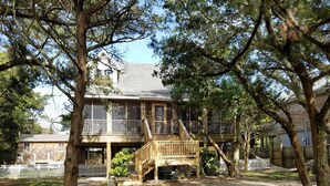 A two-story wooden house with a deck and a fenced yard. - Better Days: Pet friendly home with enclosed yard. Screened porch. (Ocracoke)