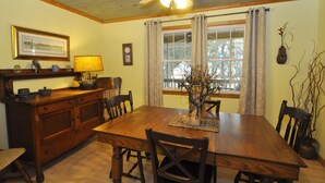 A dining room with a wooden table, chairs, a ceiling fan, and a window with curtains. - Better Days: Pet friendly home with enclosed yard. Screened porch. (Ocracoke)