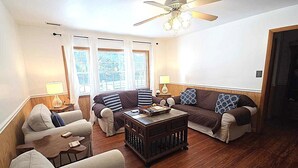 A living room with two sofas, a coffee table, and a wooden floor. - Better Days: Pet friendly home with enclosed yard. Screened porch. (Ocracoke)