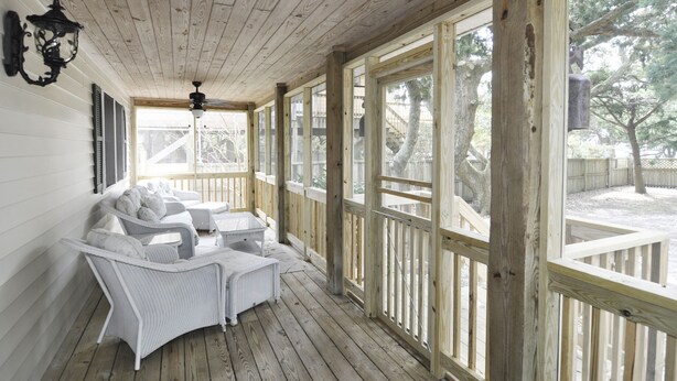 A covered porch with wicker furniture, large windows, and a wooden ceiling. - Better Days: Pet friendly home with enclosed yard. Screened porch. (Ocracoke)