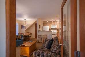 A living room with a sofa, a coffee table, and a dining area with a table and chairs. - Stoney Creek Lagoons 5 (Whistler)