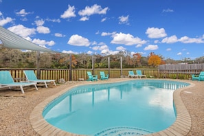Une piscine avec des chaises bleues et une clôture en bois en arrière-plan.