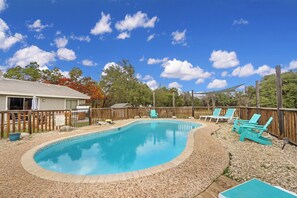 Un jardin avec une piscine, une terrasse en bois et un espace salon extérieur.