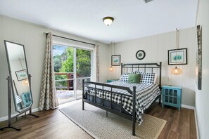 Un dormitorio con una cama, un espejo, una ventana y una puerta que da a un espacio al aire libre.