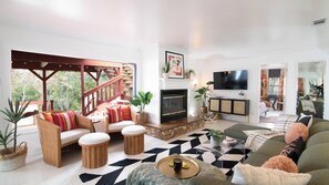 Un salón amplio con chimenea, televisor y vistas al exterior.