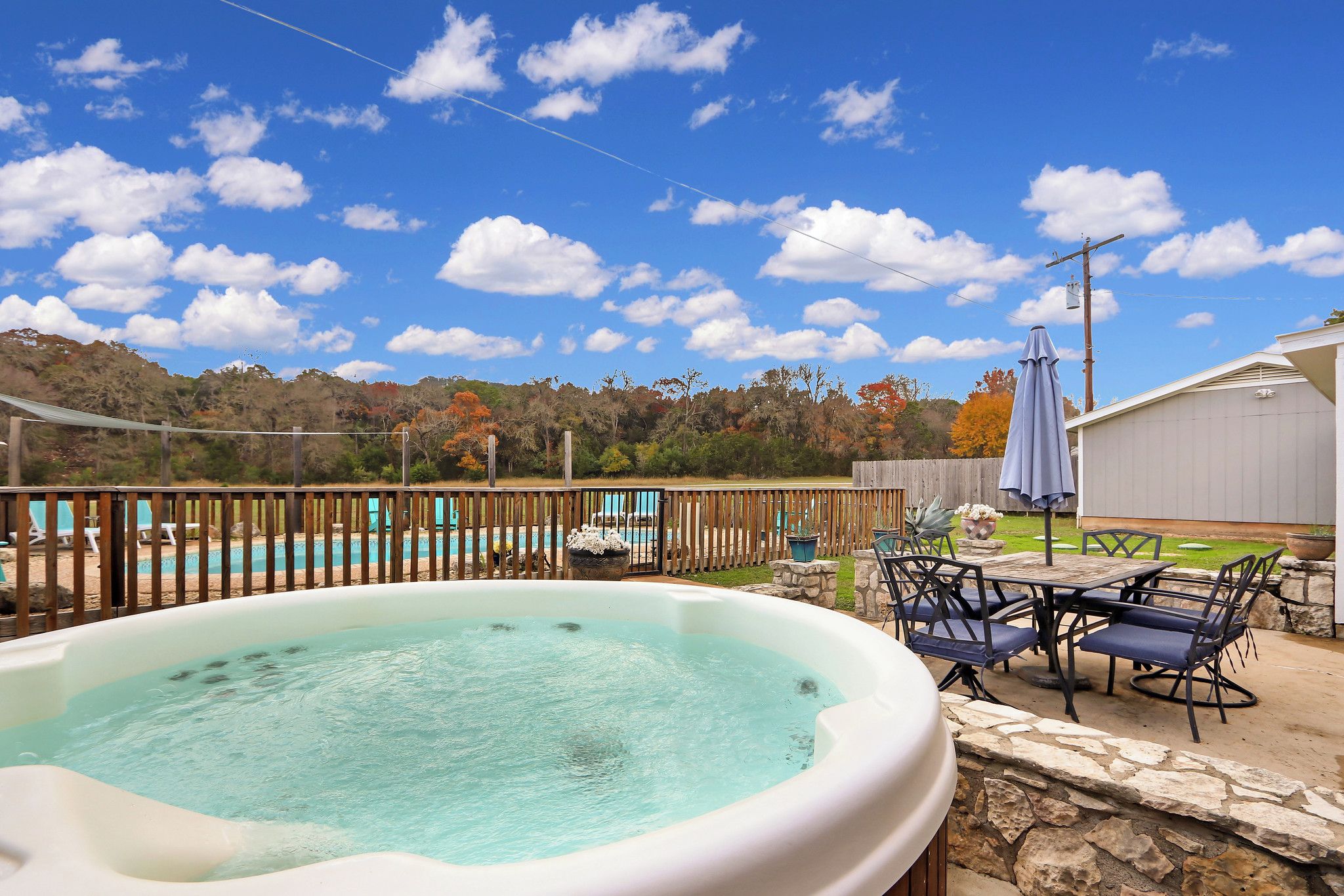 Un jardin avec un jacuzzi, du mobilier d’extérieur, une piscine et une terrasse en bois.