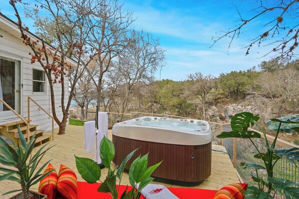 Un jacuzzi en una terraza de madera con vistas a un paisaje natural.