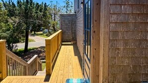 Eine Holzterrasse mit einer blauen Matte, einem Hollerdgeländer und freiem Blick auf die Umgebung.