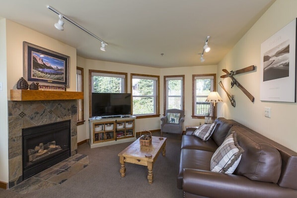 A living room with a fireplace, television, and a brown leather couch.