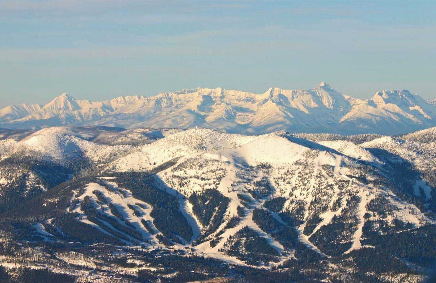 A mountainous landscape with snow-covered peaks and dense forests.
