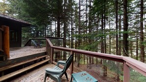 A wooden deck with a railing overlooking a forested area.
