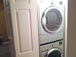 A stacked washer and dryer unit in a room with a closed door. - Cozy, Quiet Mountainside Location, Free Parking & WiFi, Huge Deck (Whistler)