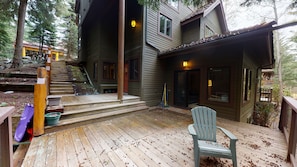 A wooden deck with a chair, steps leading to a house, and a slide. - Cozy, Quiet Mountainside Location, Free Parking & WiFi, Huge Deck (Whistler)