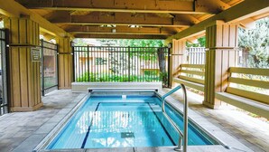 A covered swimming pool with a wooden deck, metal railings, and a view of a green garden. - Sunburst Condo 2749 - Comfortable Elkhorn Space Off of Golf Course w/ Mt View (Elkhorn)