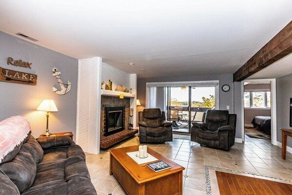 A living room with a fireplace, leather sofas, a coffee table, and a view of the outdoors.