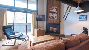 Ein gemütliches Wohnzimmer mit Kamin, großem Fenster und einer komfortablen Sitzecke.