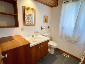 Un baño con tocador de madera, lavabo, inodoro y cortina de ducha.