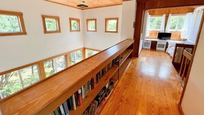 Una stanza con pavimenti in legno, una libreria in legno e una scrivania con un computer.