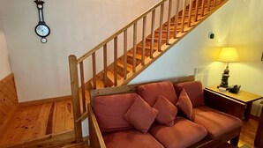Una escalera con barandillas de madera que lleva a una plataforma. Un reloj está colgado en la pared sobre la escalera.