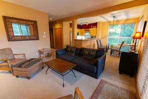 A living room with a sofa, armchairs, a coffee table, and a dining area with a table and chairs.