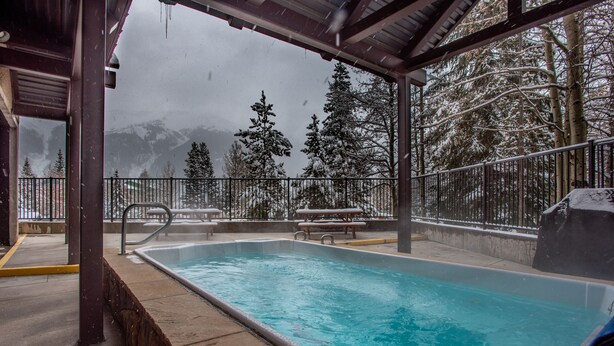 A swimming pool with a view of snow-covered trees and mountains in the background. - Ski-in Ski-Out free wifi, underground parking, middle of Center Village. (Copper Mountain)