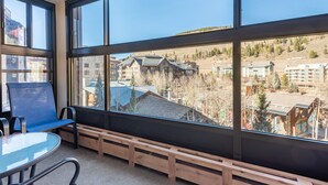 A room with a large window, a wooden bench, and a glass table. - Ski-in Ski-Out free wifi, underground parking, middle of Center Village. (Copper Mountain)