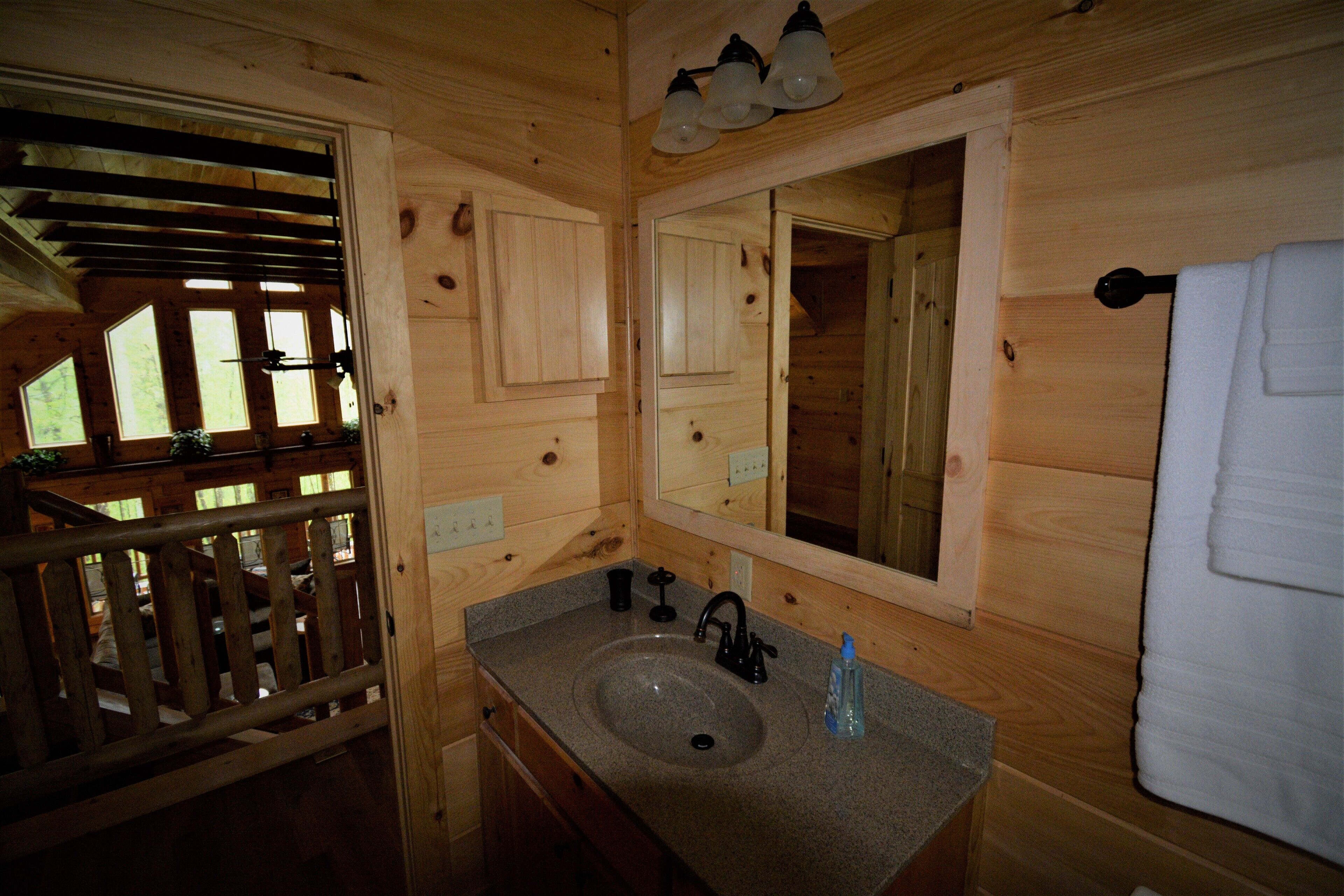 A wooden cabin bathroom with a granite sink, a mirror, and a towel hanging on the wall.