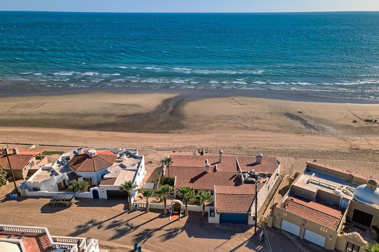 Une propriété située sur la côte, avec vue sur la plage, un espace de stationnement et un bâtiment doté d’un toit en tuiles.