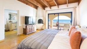 Une chambre à coucher avec un lit, une télévision, une cheminée et une vue sur la mer.