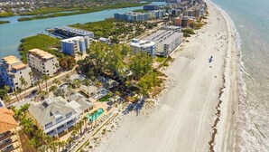 Zona hotelera frente al mar con propiedades en la playa, un puerto deportivo y un río.